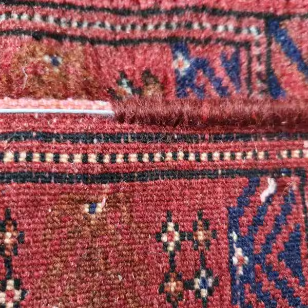 Artisan performing hand stitched rug binding edge repair on Persian rug Auckland
