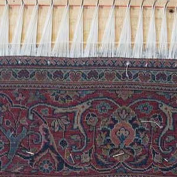 Professional Persian rug fringe repair in Auckland with complete tassel renewal on a fine rug, restoring damaged fringe with detailed hand-crafted restoration techniques