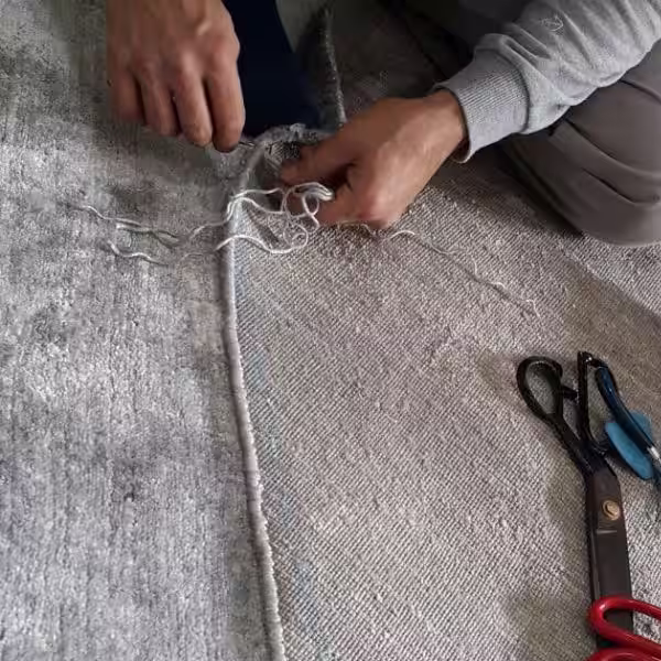 Close-up of rug edge binding and finishing after resizing and reshaping in Auckland workshop