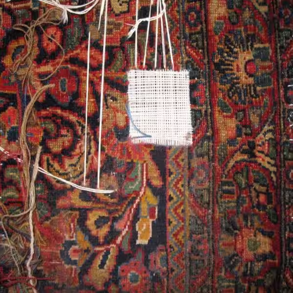 Halfway completed rug reweaving showing structural reconstruction of damaged handmade rug weave during repair process