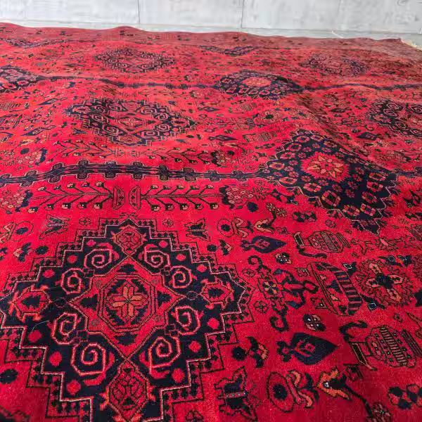 Rug stretching and tension correction being performed in workshop to restore flatness and structural balance