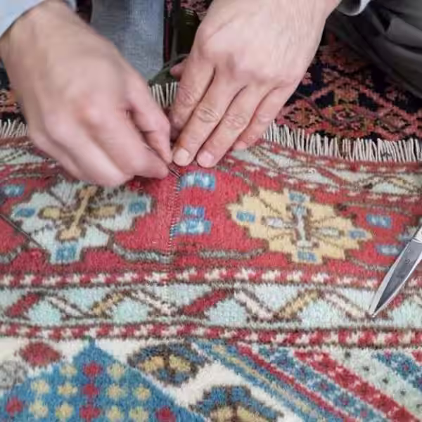 Technician adding new pile to restore density in worn rug sections
