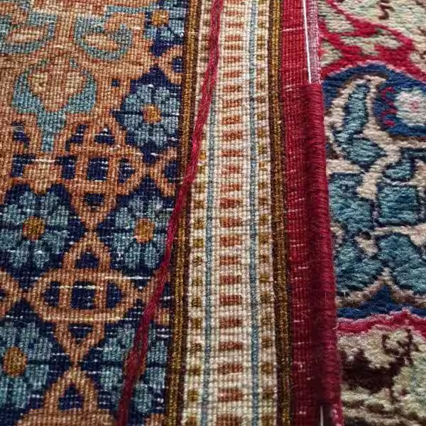 Specialist applying precise edging to handmade oriental rug to prevent fraying and strengthen structure