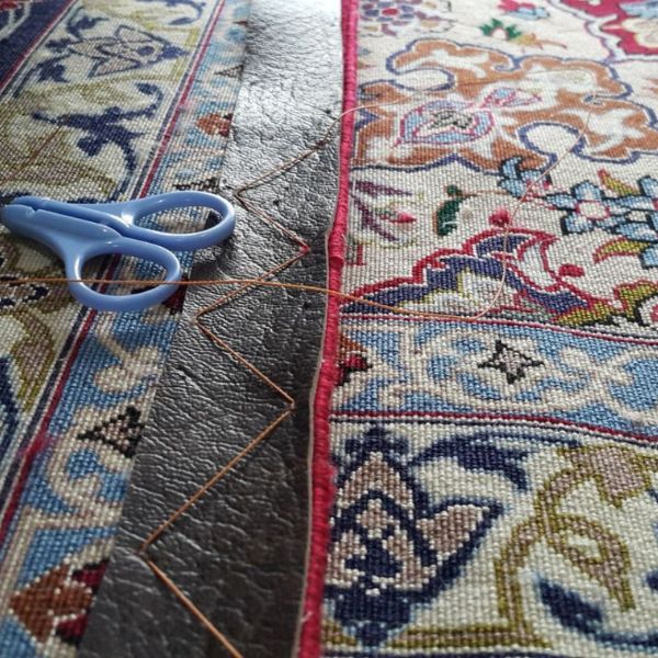 Applying leather strip reinforcement to the back edge of a rug to stabilise and flatten curled borders