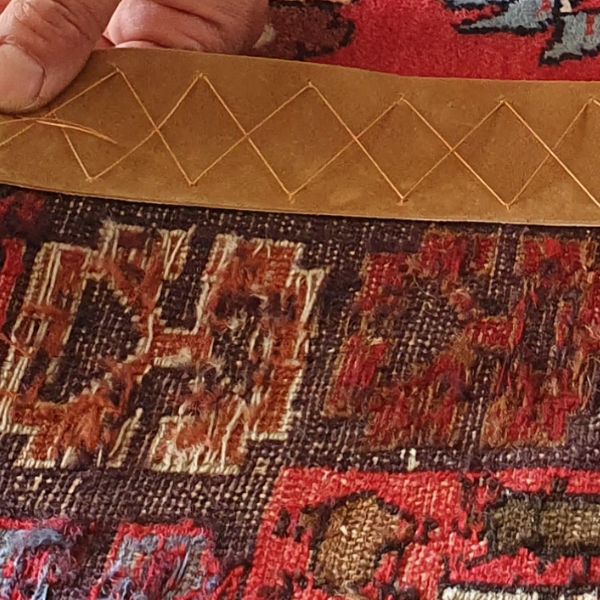 Rug edge leathering showing 5cm leather strip reinforcement attached to the back of a handmade rug edge in Auckland workshop