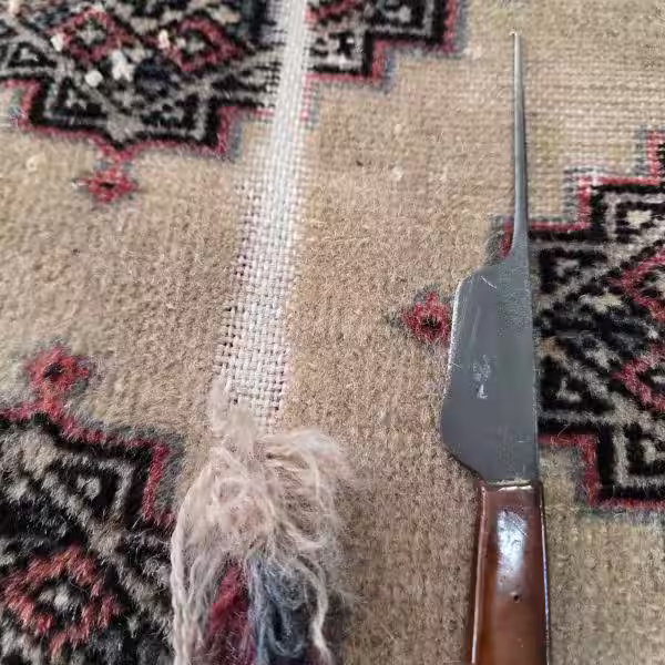 Restoring missing rug pile by rebuilding worn fibre areas and knots