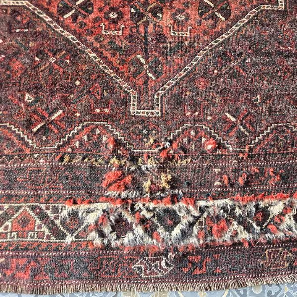 Wool rug undergoing pile repair with fibre rebuilding in progress to restore texture and surface density