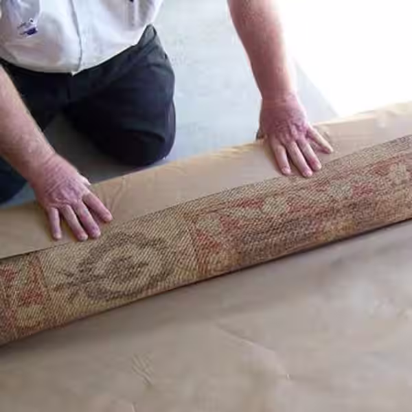 Rug being carefully rolled for long-term storage to prevent folding damage and fibre stress